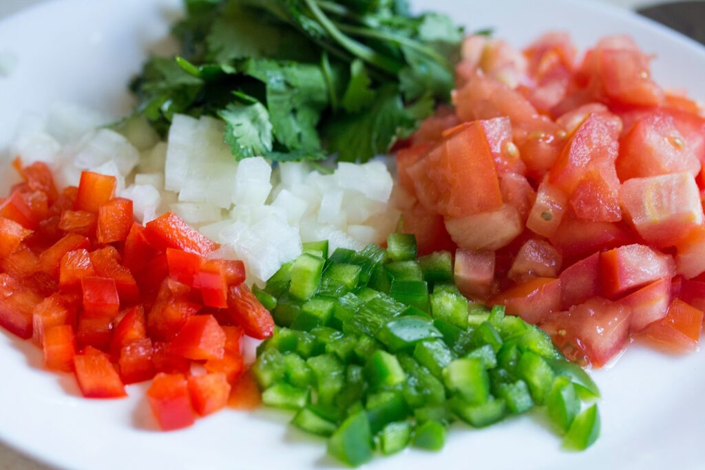 "Fresh chopped vegetables—tomatoes, onions, peppers, and cilantro—on a plate, symbolizing KeyBuzz Digital’s recipe-style approach to mixing SEO, content, and strategy for small business growth