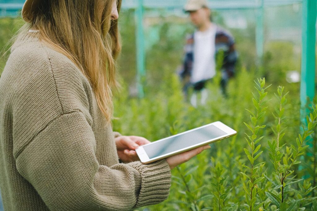 Small business owner using a tablet in a greenhouse to track growth and performance — reflecting KeyBuzz Digital’s approach to blending data, technology, and strategy for sustainable business success.
