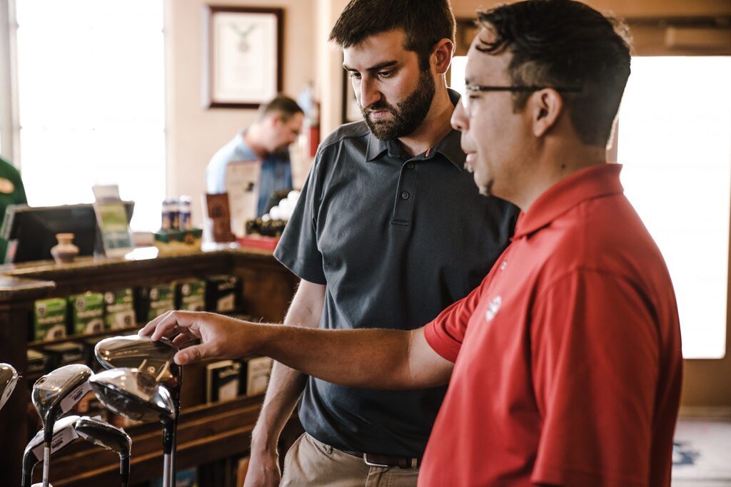 Sales professional helping a customer choose the right golf clubs — a reminder from KeyBuzz Digital that the right digital marketing tools, like the right gear, make all the difference in driving business success.