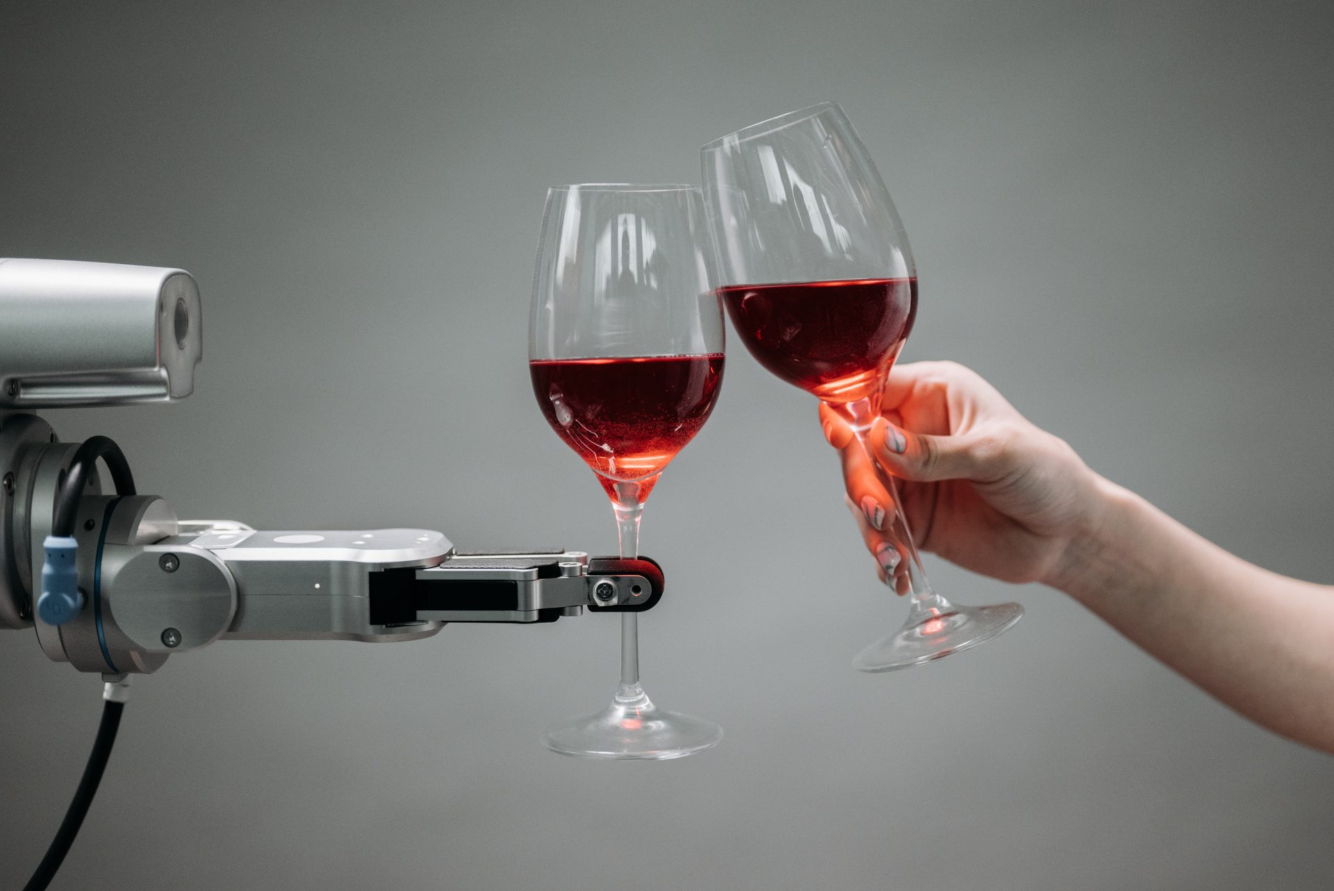 Robot arm clinking wine glasses with a human hand symbolizing the blend of technology and hospitality innovation that keybuzz digital brings to business growth   keybuzz digital marketing services
