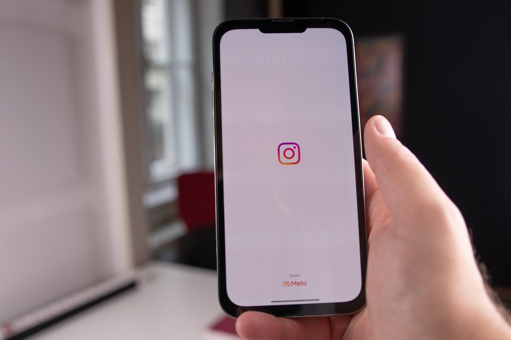Hand holding smartphone with Instagram app loading screen, showcasing Meta branding