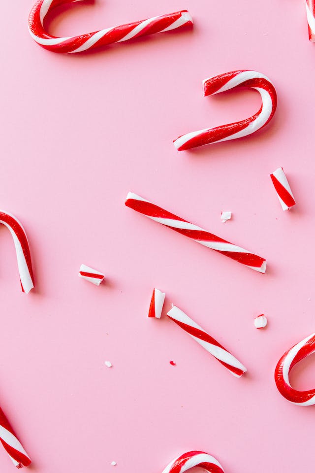 Broken red and white candy canes scattered on a pink background, symbolizing holiday marketing challenges and creative seasonal campaigns