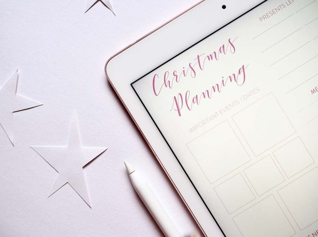 Tablet displaying a Christmas planning template with stylus and star decorations, symbolizing holiday preparation and seasonal marketing strategy