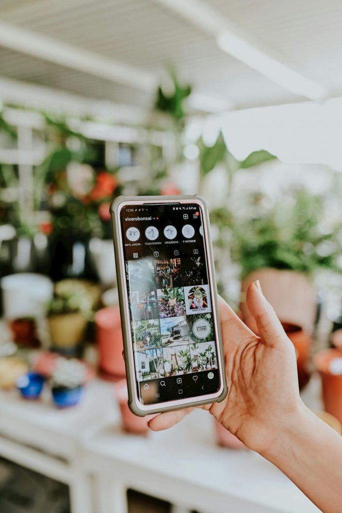 Hand holding a smartphone showing an Instagram business profile with curated posts, stories, and highlights, representing social media marketing strategy in action.